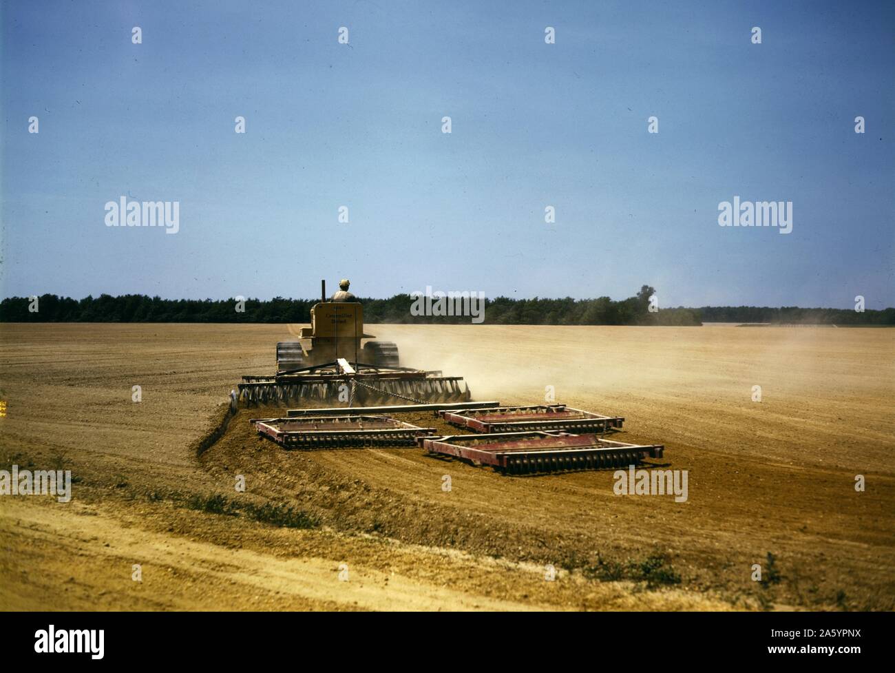 Harrowing a field with a diesel tractor at Seabrook Farm, Bridgeton, New Jersey, USA. Created by photographer John Collier, (1913-1992). Colour. June 1942. Stock Photo