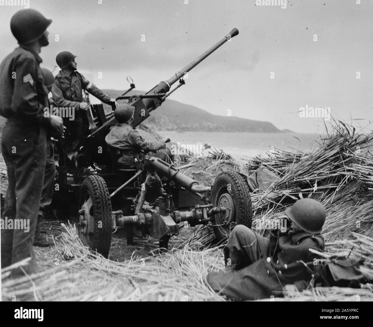 Anti-aircraft bofors gun in at position on a mound overlooking the beach in Algeria with a United States anti-aircraft artillery crew in position. 1943. Stock Photo