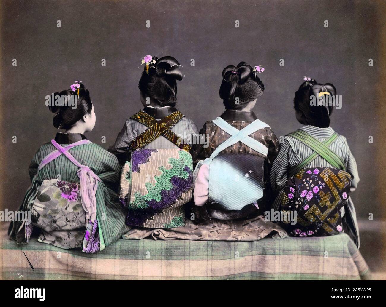 Hand coloured photograph of Geishas sitting with their backs toward the camera. Dated 1900 Stock Photo