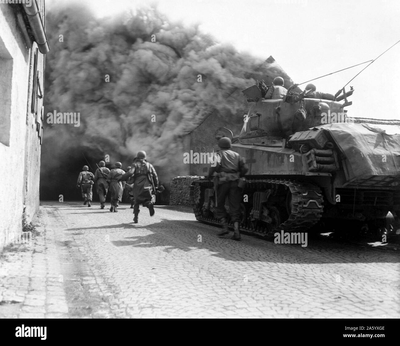 Photograph of M4 Sherman tank move through a smoke filled street in Wernberg, Germany. Dated 1943 Stock Photo