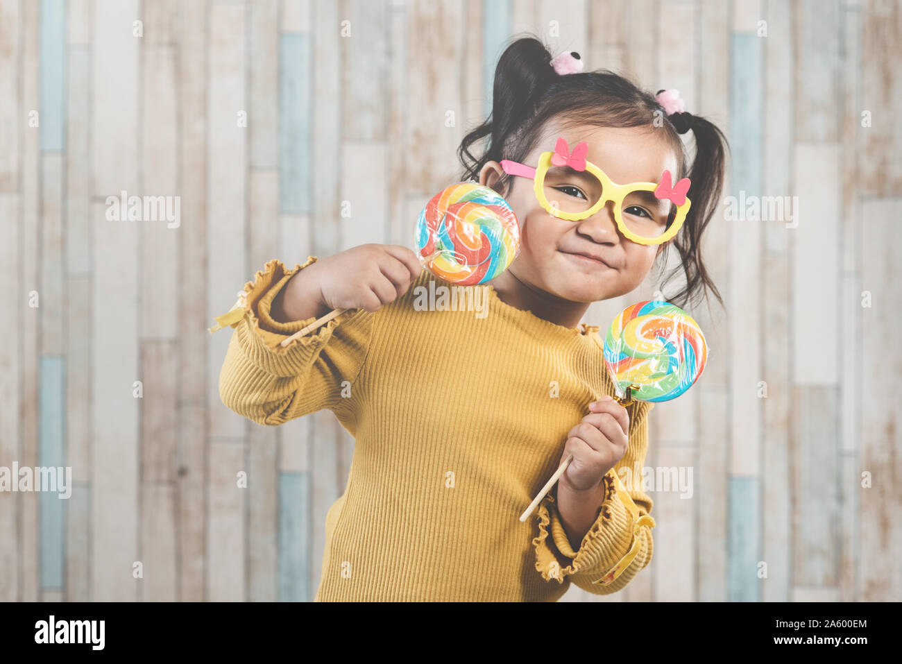 Cute little asian girl holding and eating a colorful lollipop. concept of oral care and candy day Stock Photo