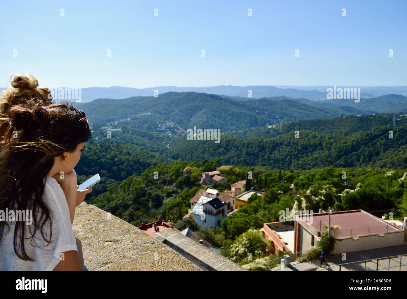 A young girl viewing the Serra de Collserola mountain range at Tibidabo in Barcelona, Spain Stock Photo