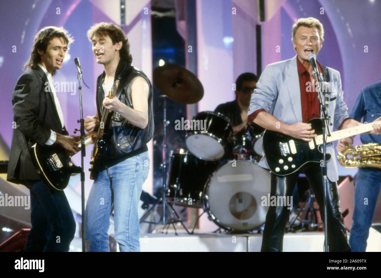 Jean-Jacques Goldman, Michael Jones and Johnny Hallyday performing a song  from Johnny's new album ('Gang') on the set of a television show. December  1986 Stock Photo - Alamy