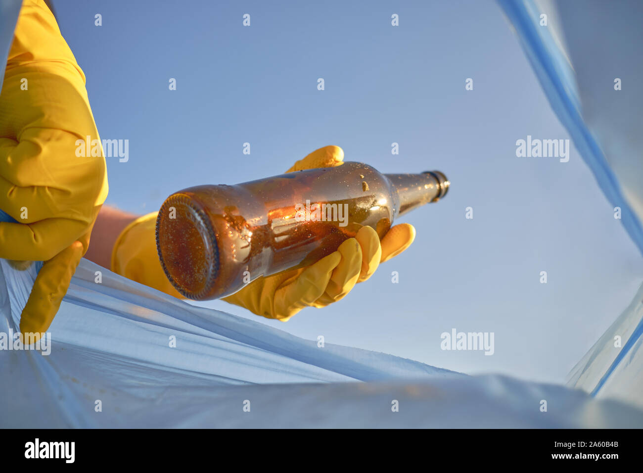 Hand of a conscious man in a yellow rubber glove puts a used brown ...