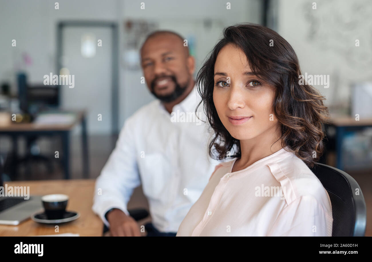 Young businesswoman sitting with a colleague in an office Stock Photo