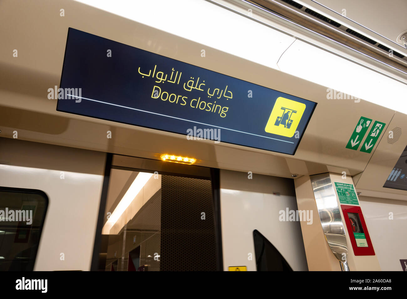 A bilingual digital sign indicating 'Doors closing' in English and Arabic on the passenger cabin on the Doha Metro, Qatar Stock Photo