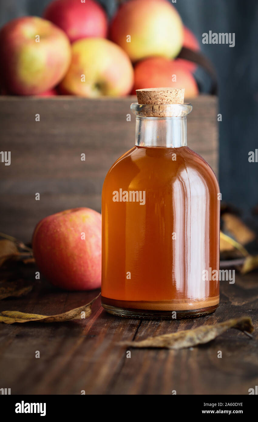 Apple cider vinegar with the mother, yeast and healthy bacteria, surrounded by fresh apples