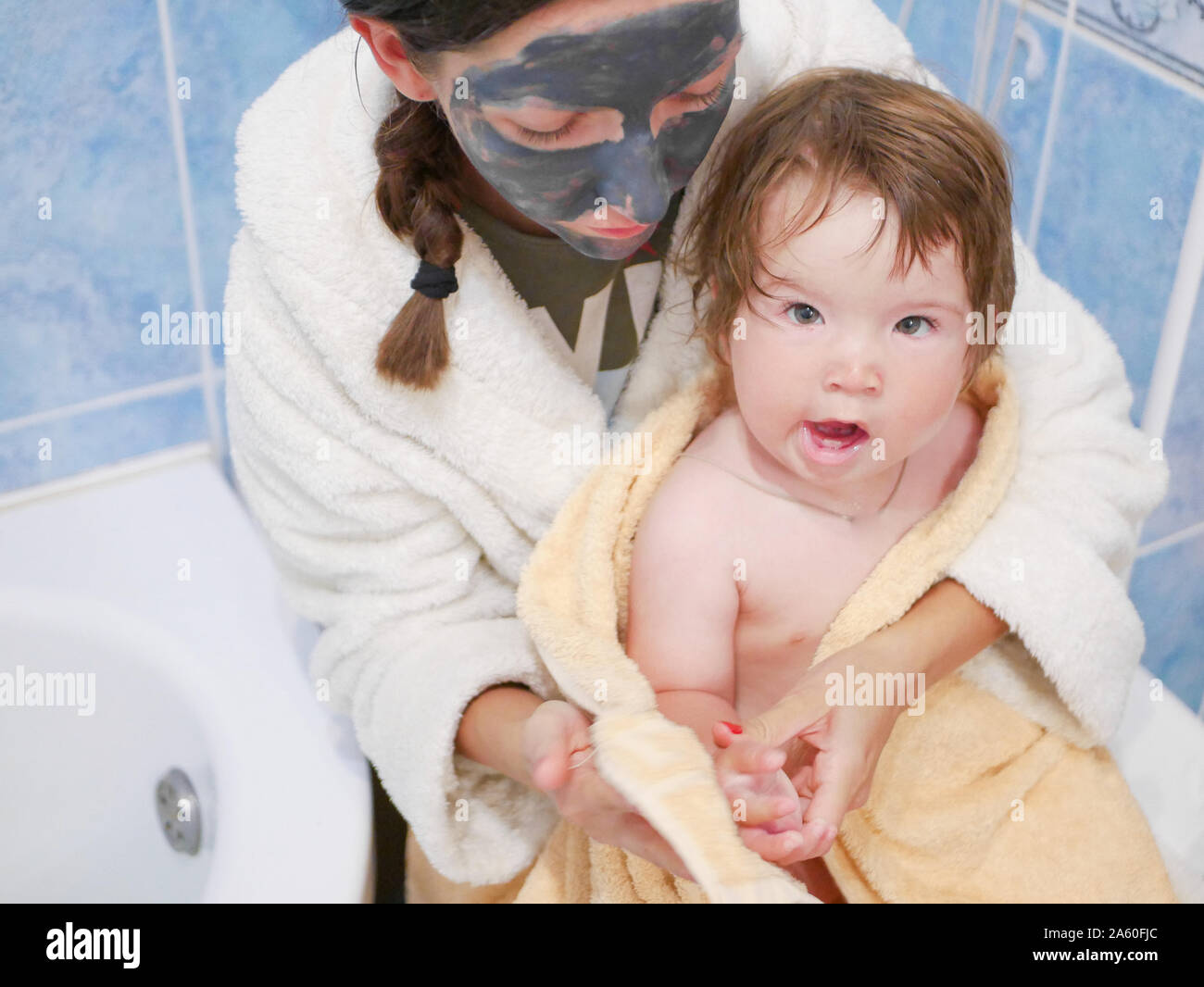 baby with mother in the bathroom. Mother holding her baby in a towel in