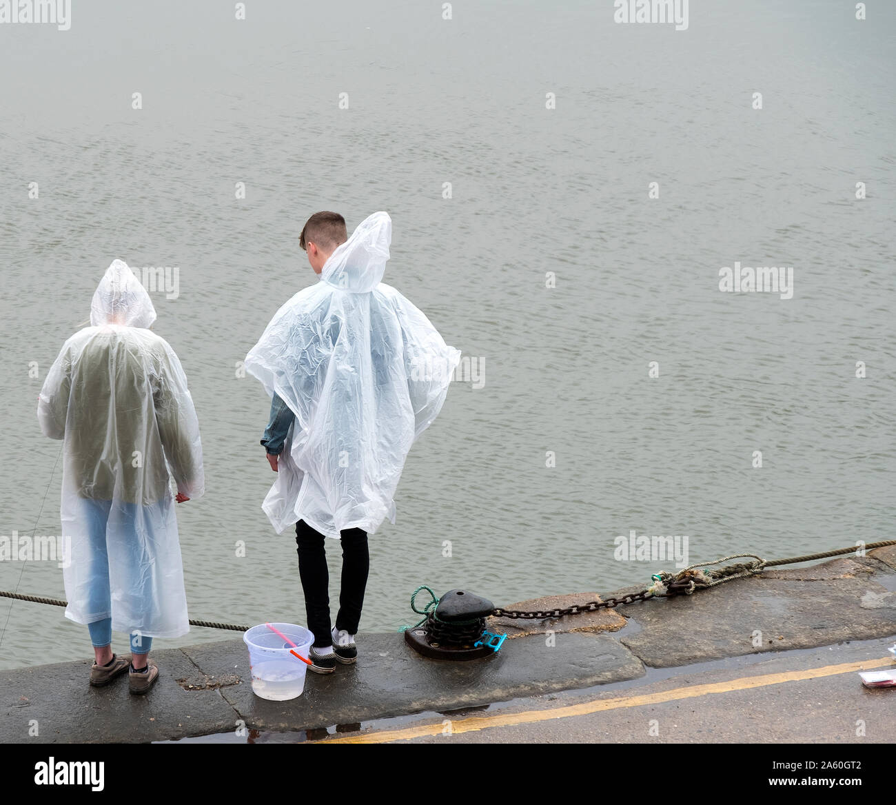Two young people crab fishing in the rain Stock Photo
