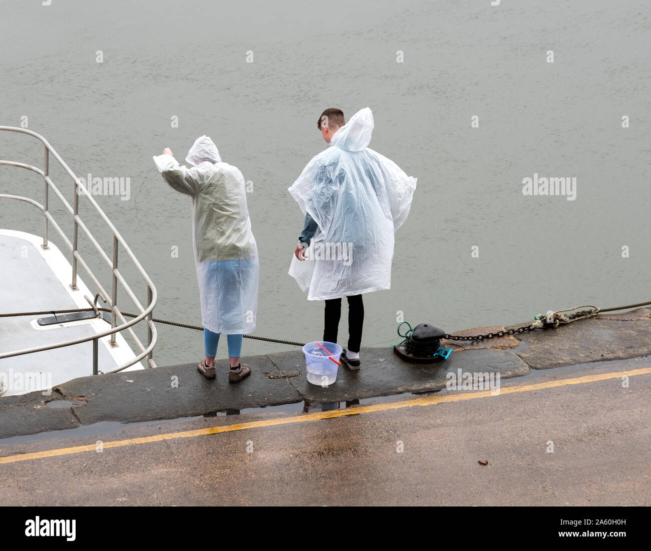 Two young people crab fishing in the rain Stock Photo