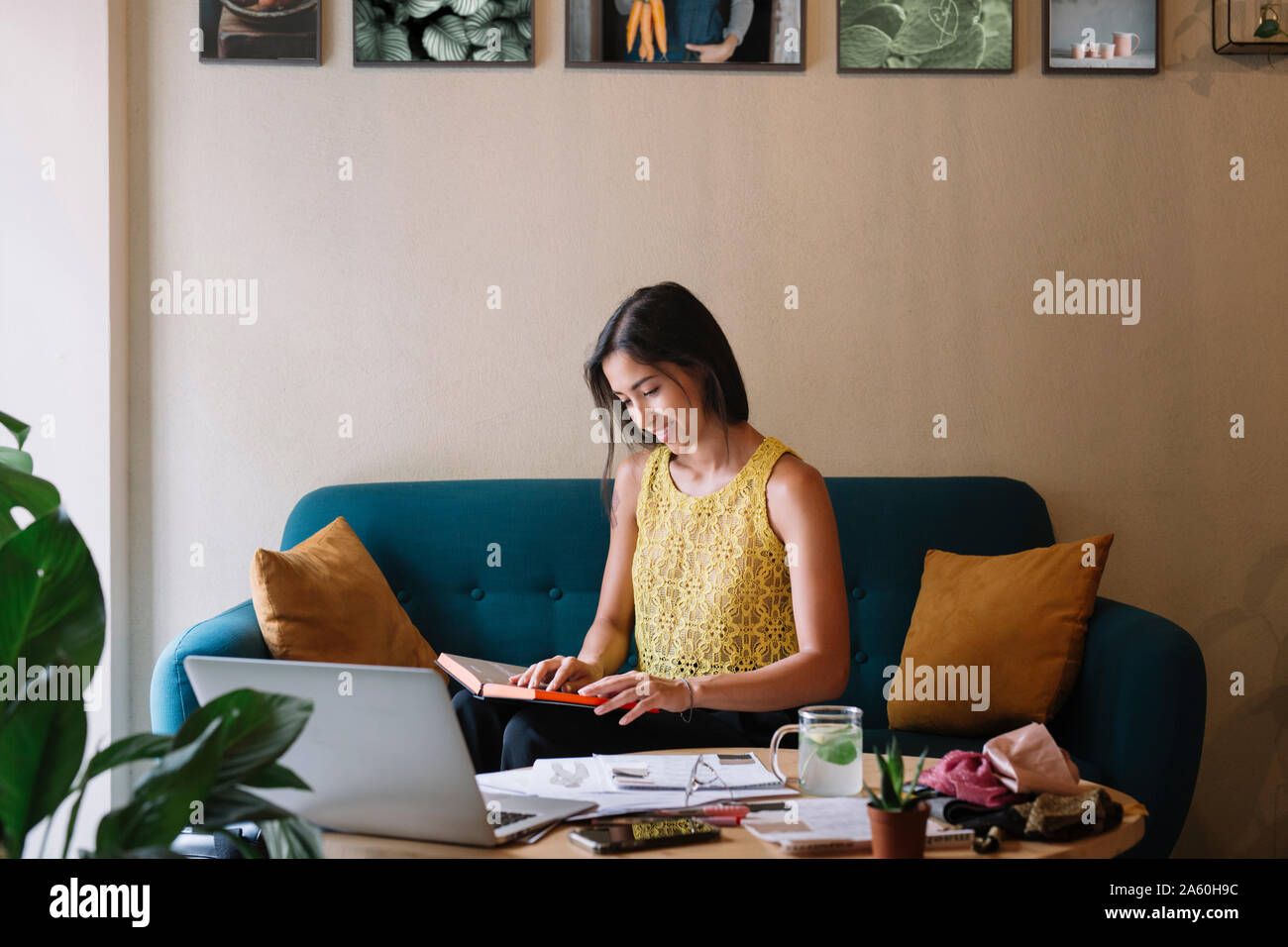 Smiling fashion designer sitting on couch working on a new collection Stock Photo