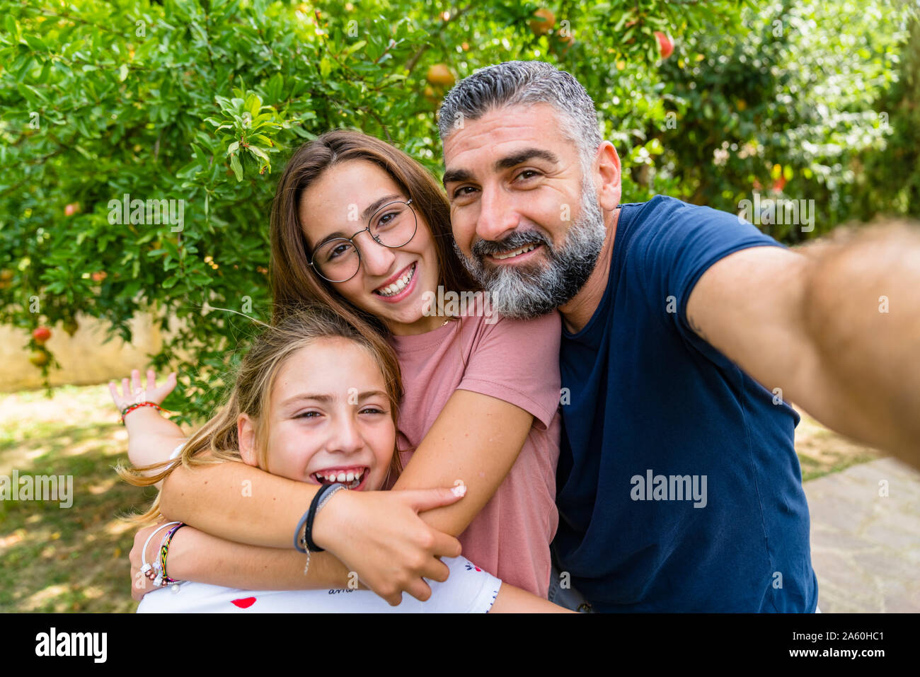Happy father with two daughters taking selfie in garden Stock Photo
