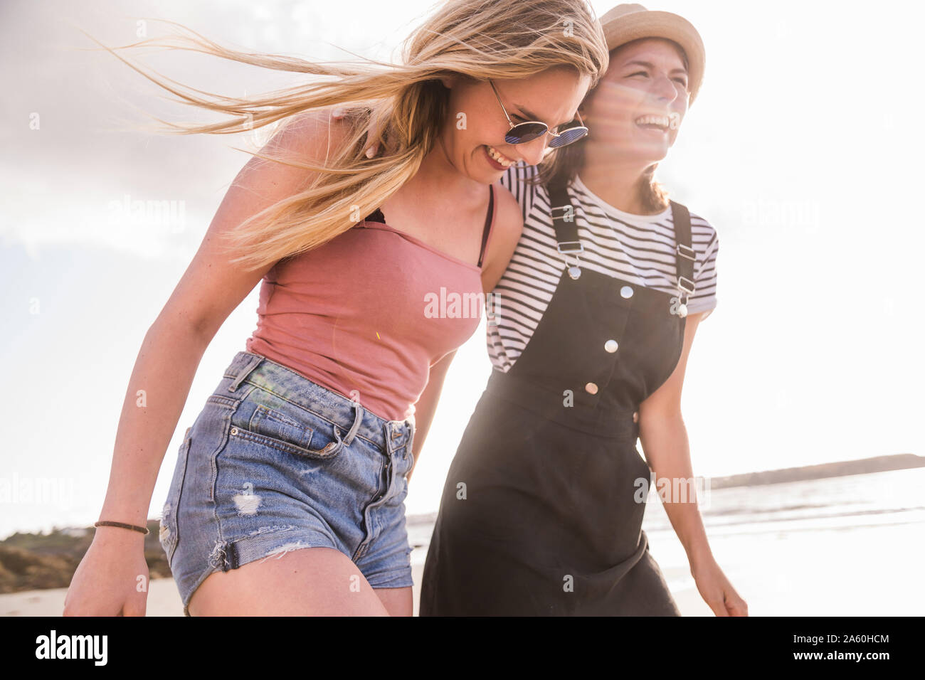 Two girlfriends having fun, walking on the beach Stock Photo