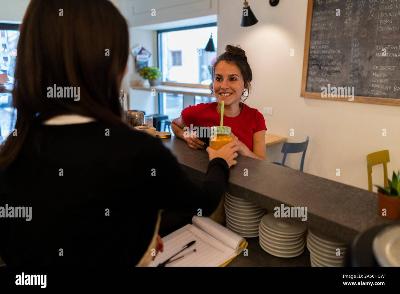 Smiling young woman at the counter in a cafe Stock Photo