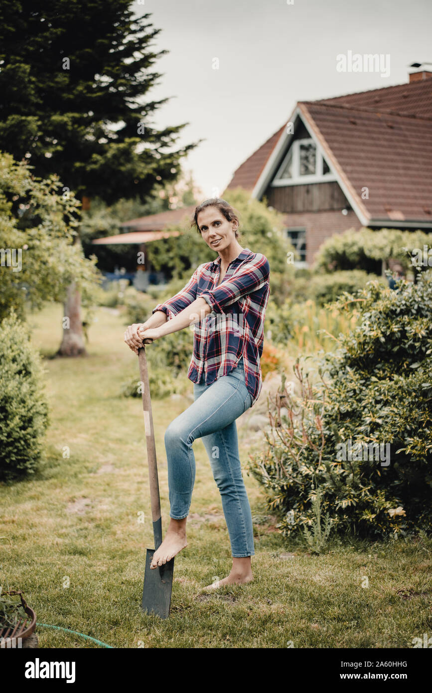 Proud home owner standing in her garden with a spade Stock Photo