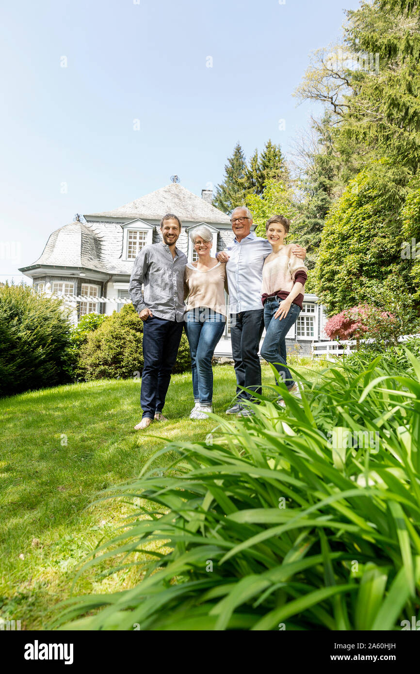 Happy senior couple with adult children standing in garden of their home Stock Photo