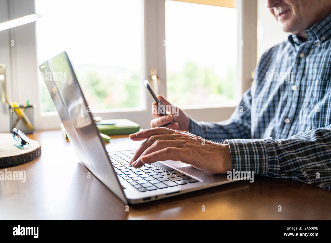 Senior man using laptop and smartphone at home Stock Photo