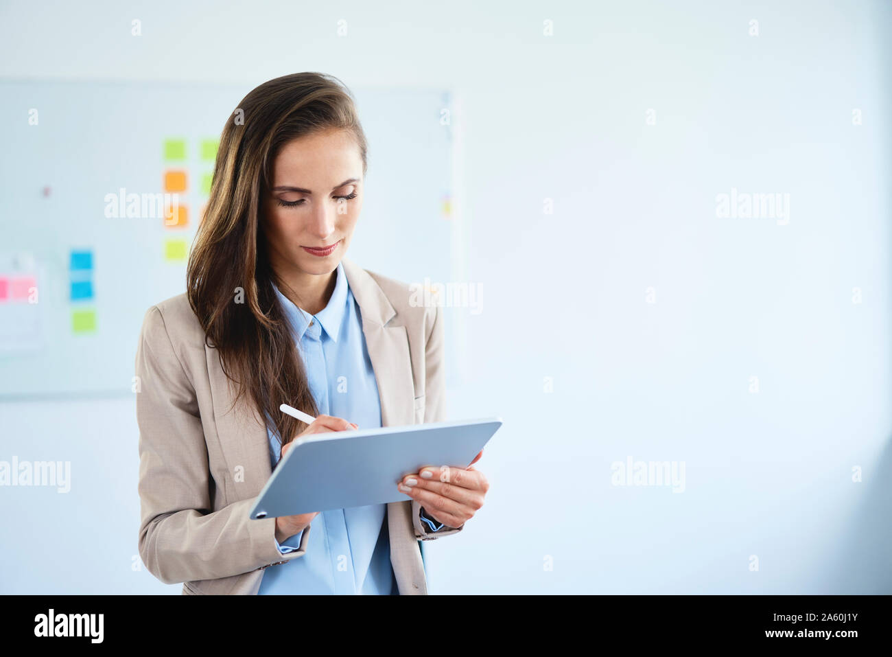 Young businesswoman writing on tablet in office Stock Photo