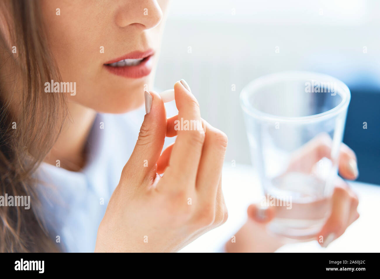 Close up of woman taking pill Stock Photo