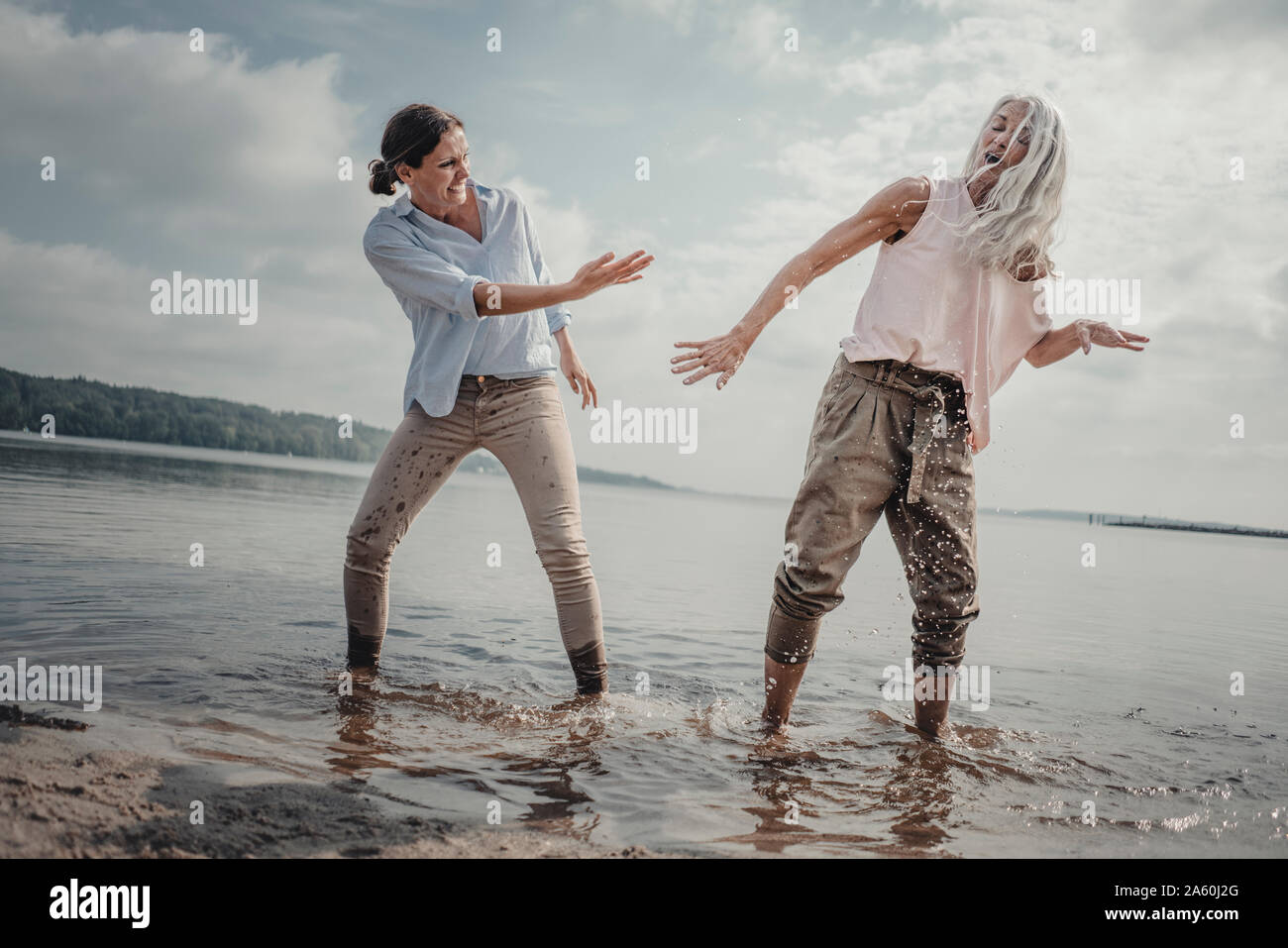 Mother and daughter nhaving fun on the beach, splashing water Stock ...