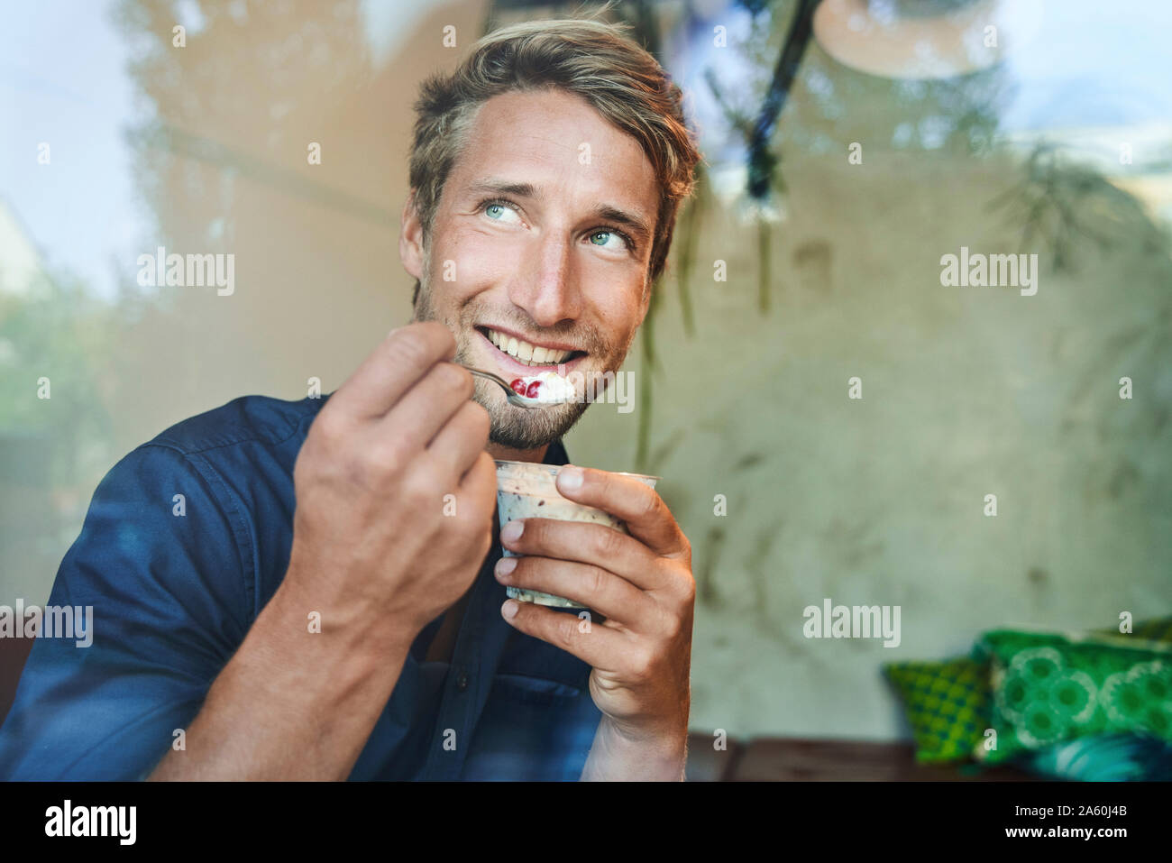 Portrait of smiling young man eating muesli Stock Photo