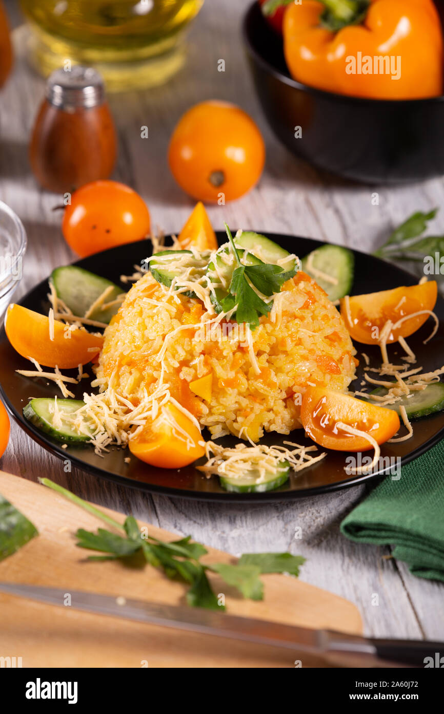 Cooked rice with carrots and sweet peppers on the kitchen table Stock Photo