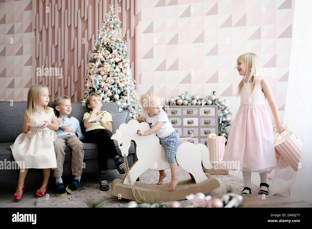 Five children playing and eating cookies in the living room at Christmas time Stock Photo