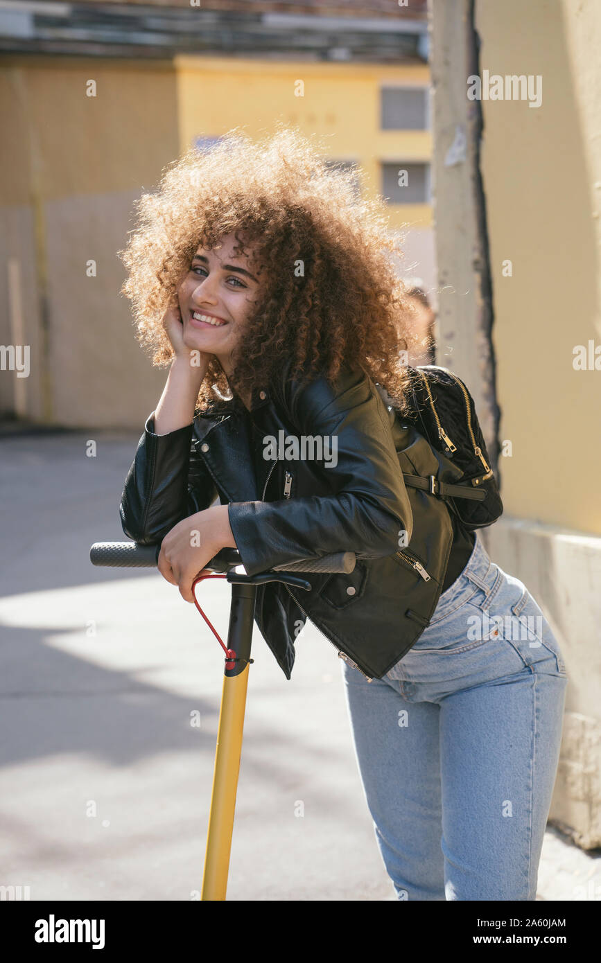 Portrait of happy teenage girl with scooter in the city Stock Photo