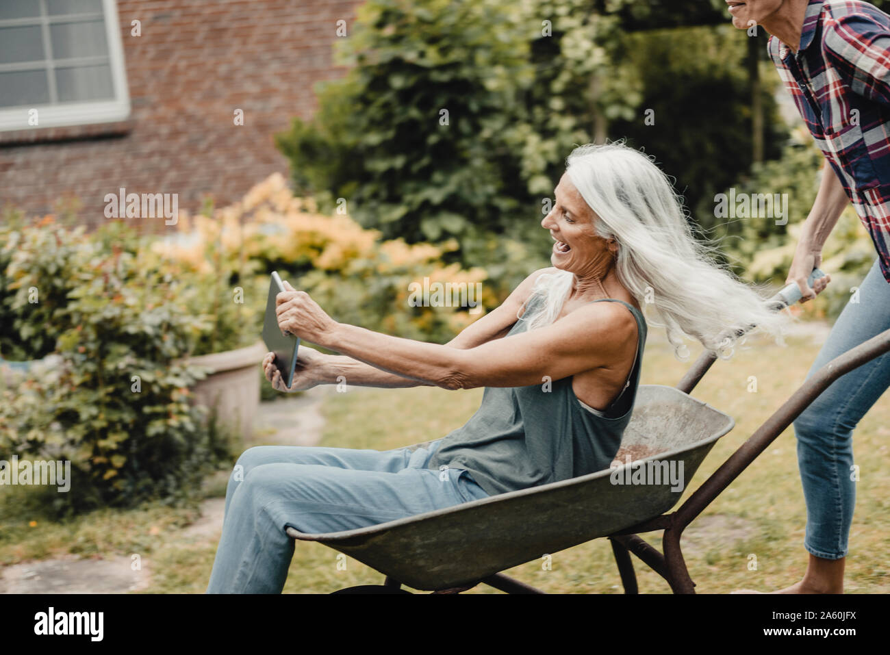 Senior woman sitting push cart, using digital tablet Stock Photo