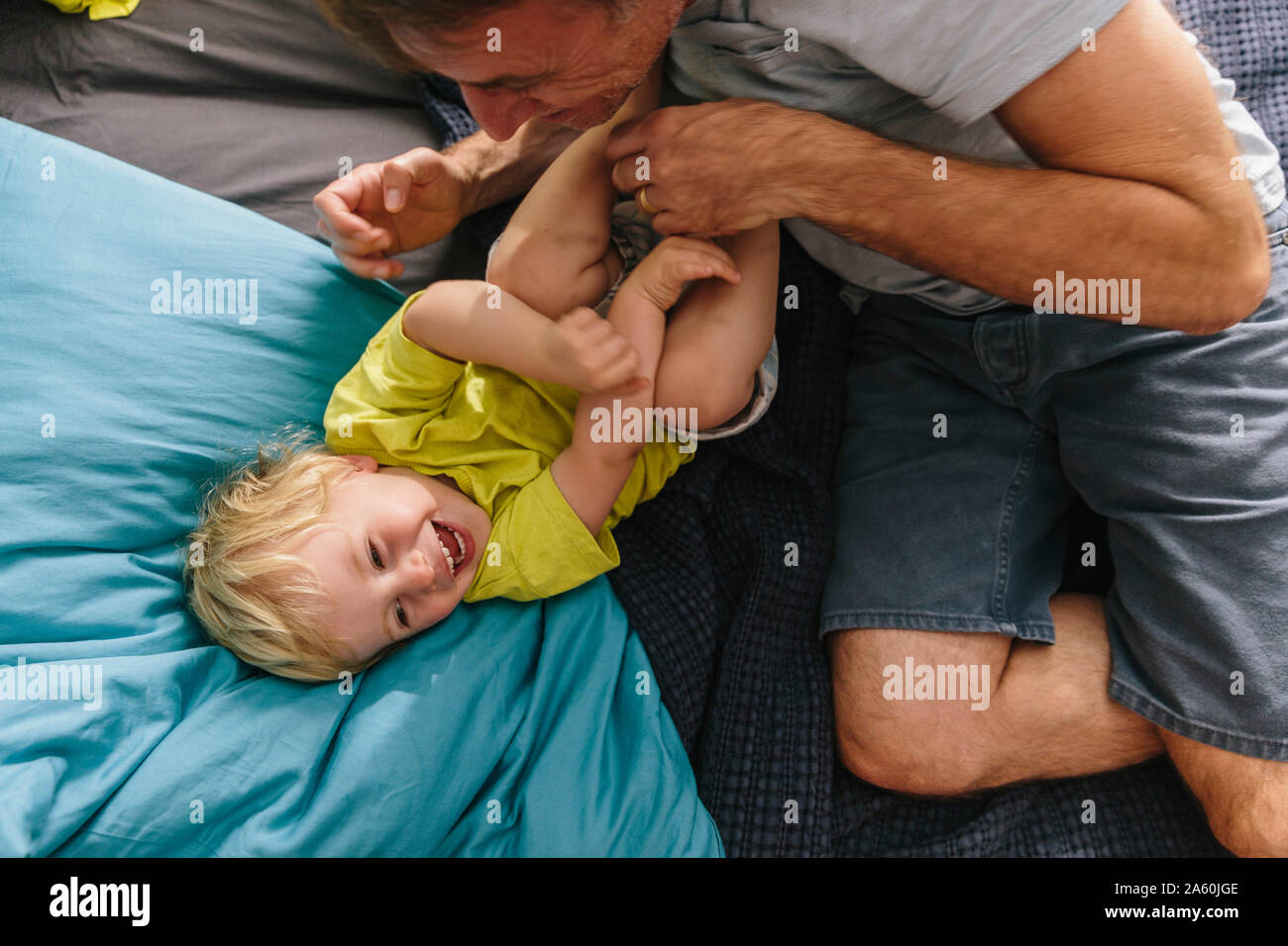 Father cuddling and tickling son on bed Stock Photo