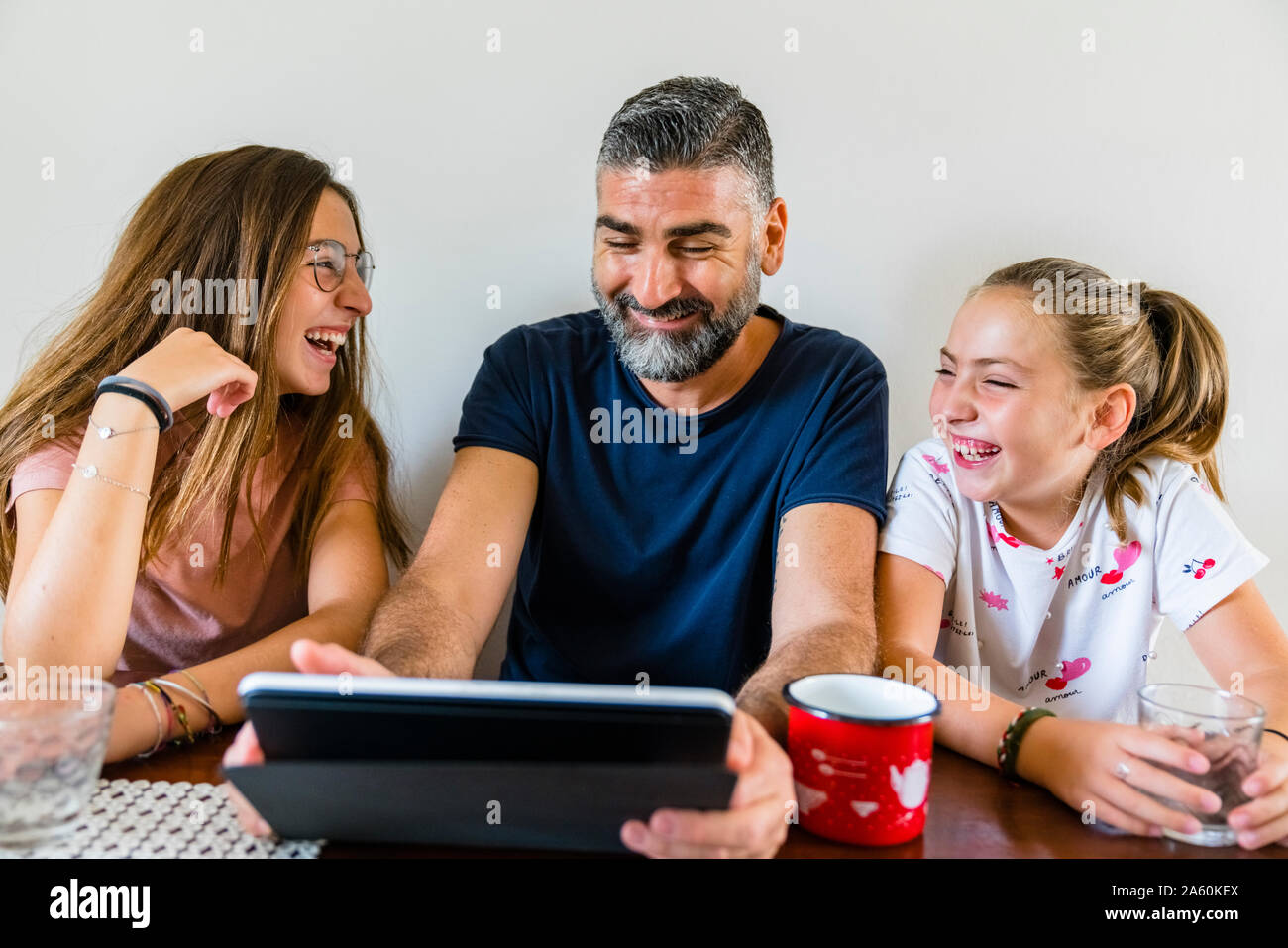 Happy father with two daughters using tablet at home Stock Photo