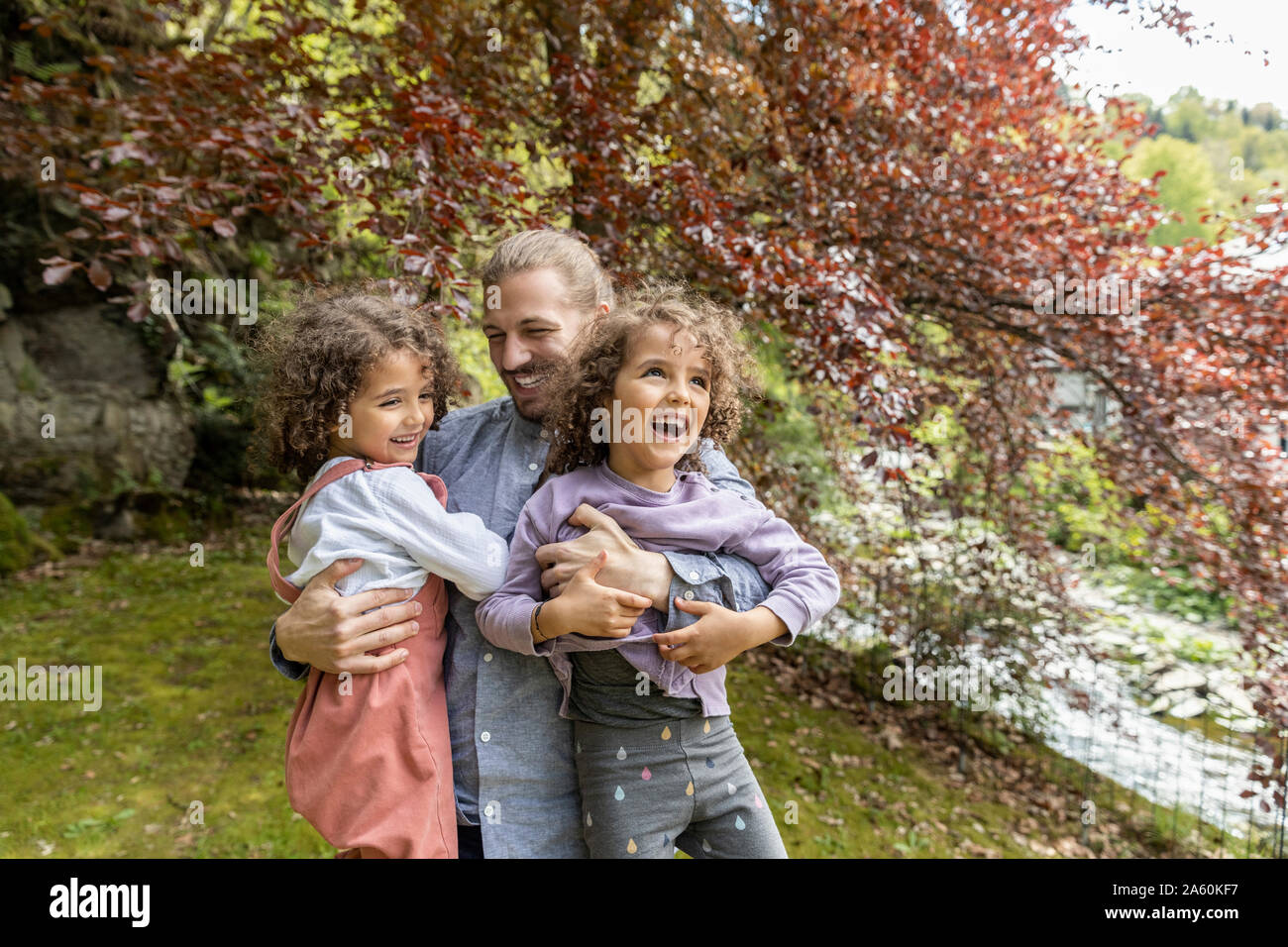 Happy father having fun with two boys in garden Stock Photo