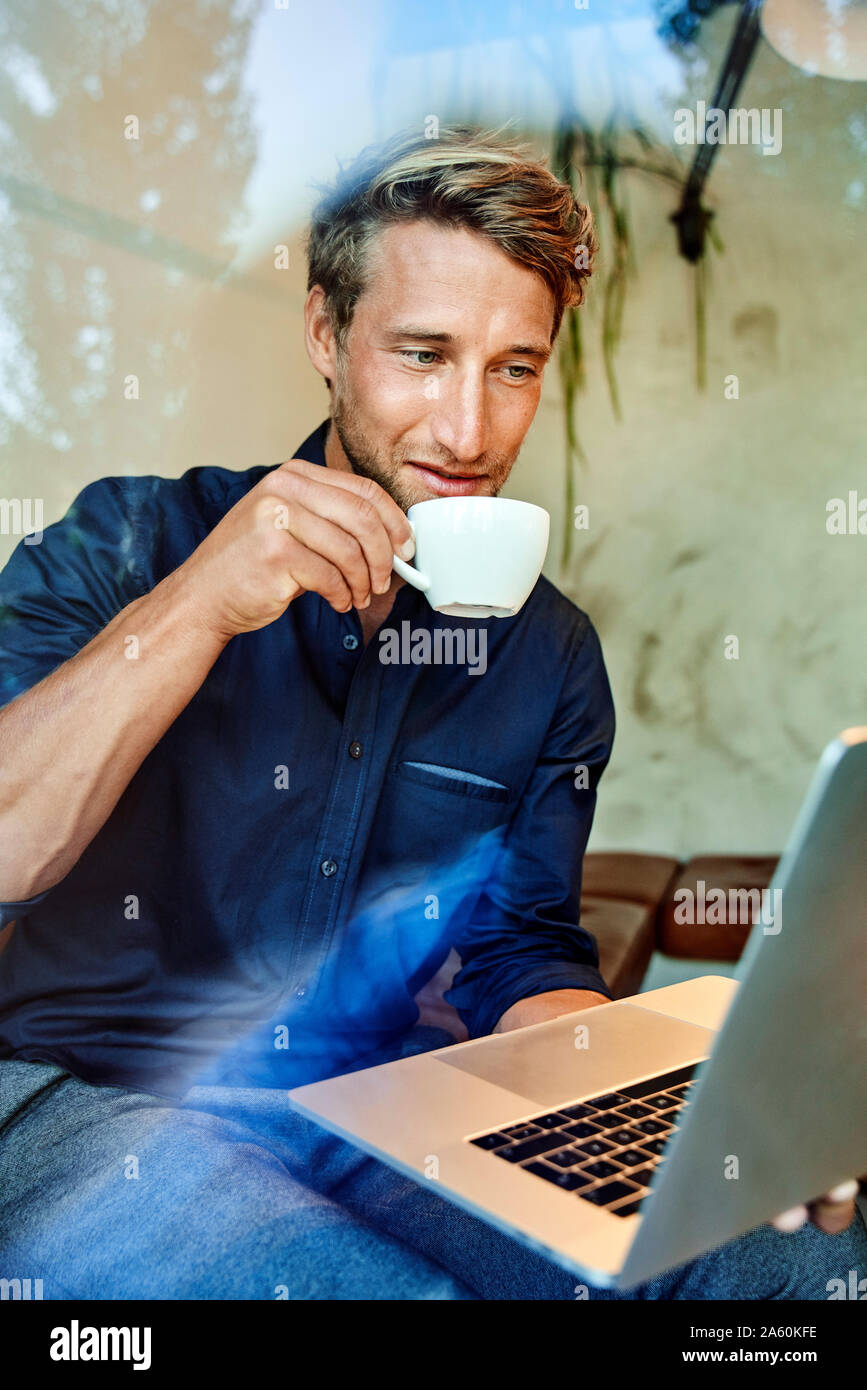 Young businessman drinking coffee and using laptop in a cafe Stock Photo