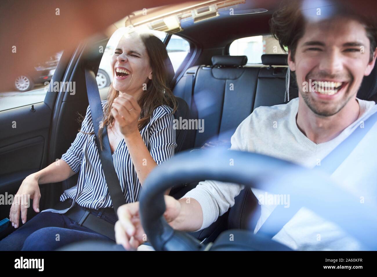 Laughing couple in a car with man driving Stock Photo Alamy