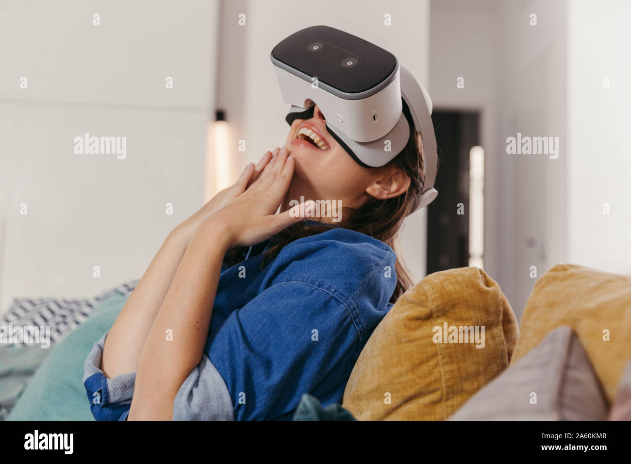 Young woman using VR glasses at home Stock Photo