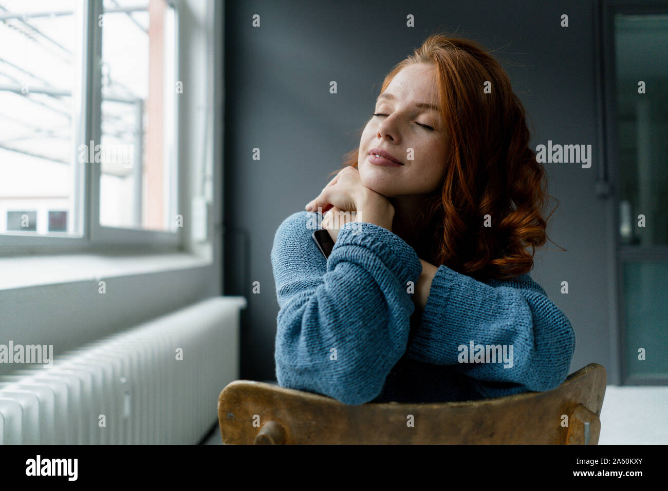 Portrait of redheaded woman with digital tablet relaxing in a loft Stock Photo