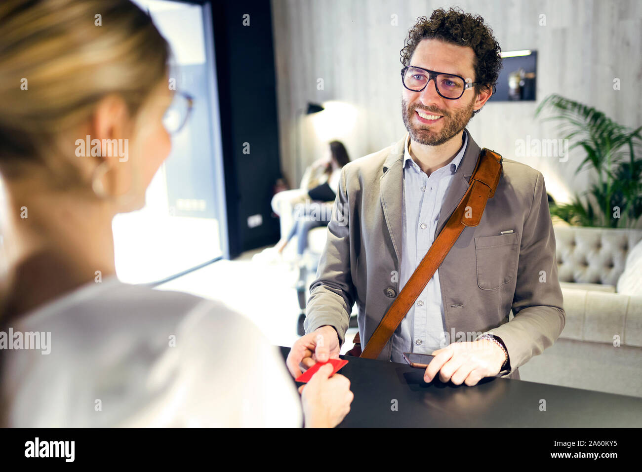 Smiling businessman handing over credit card at reception Stock Photo