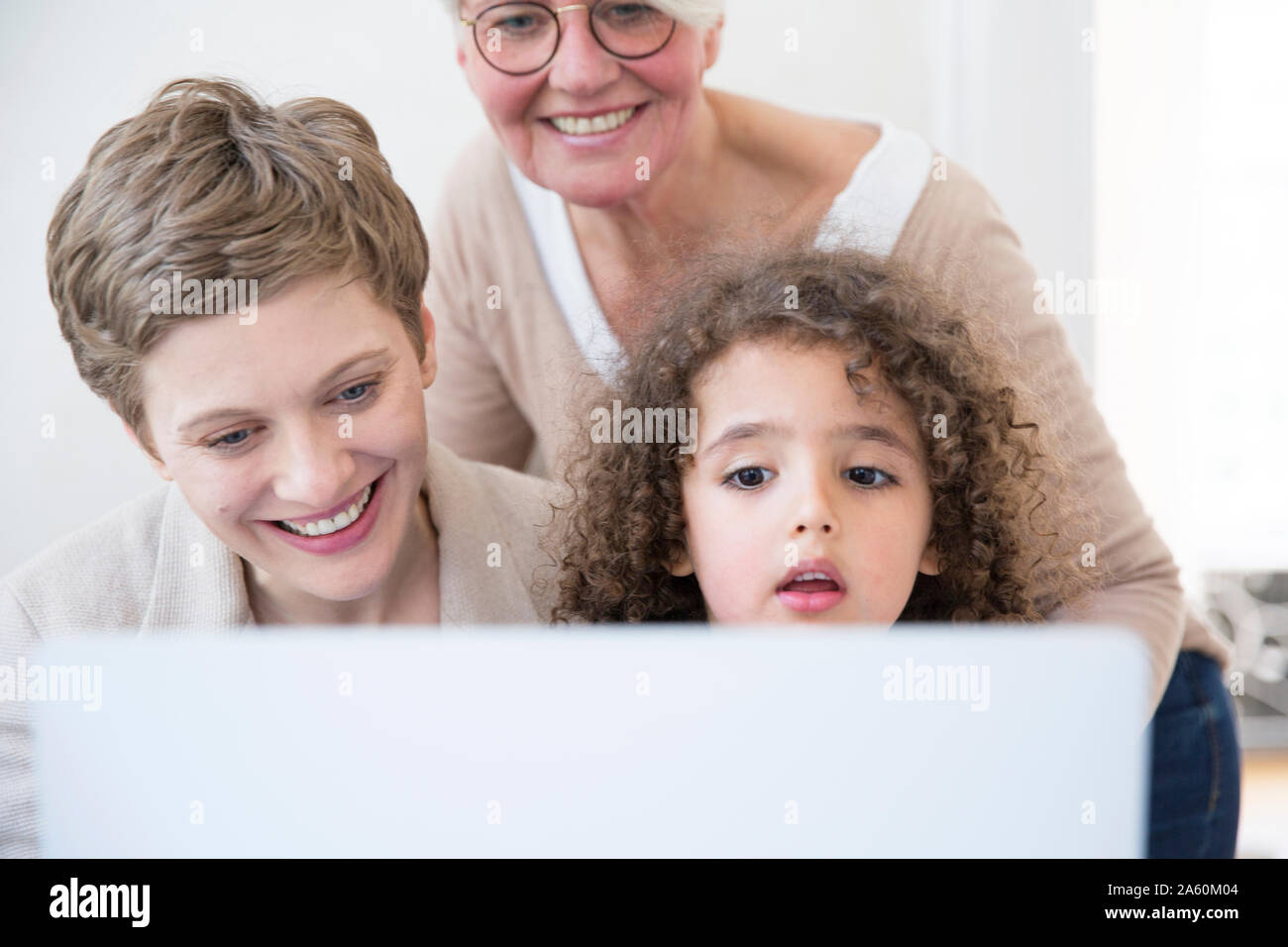 Smiling grandmother, mother and son using laptop at home Stock Photo