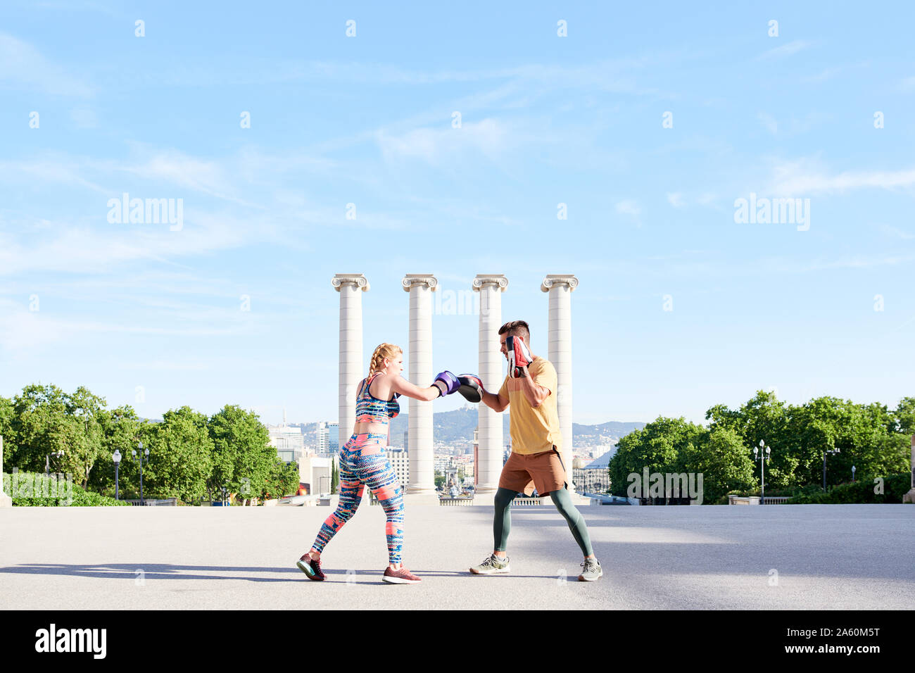 Fitness coach practicing boxing class with young woman outdoors in the city Stock Photo