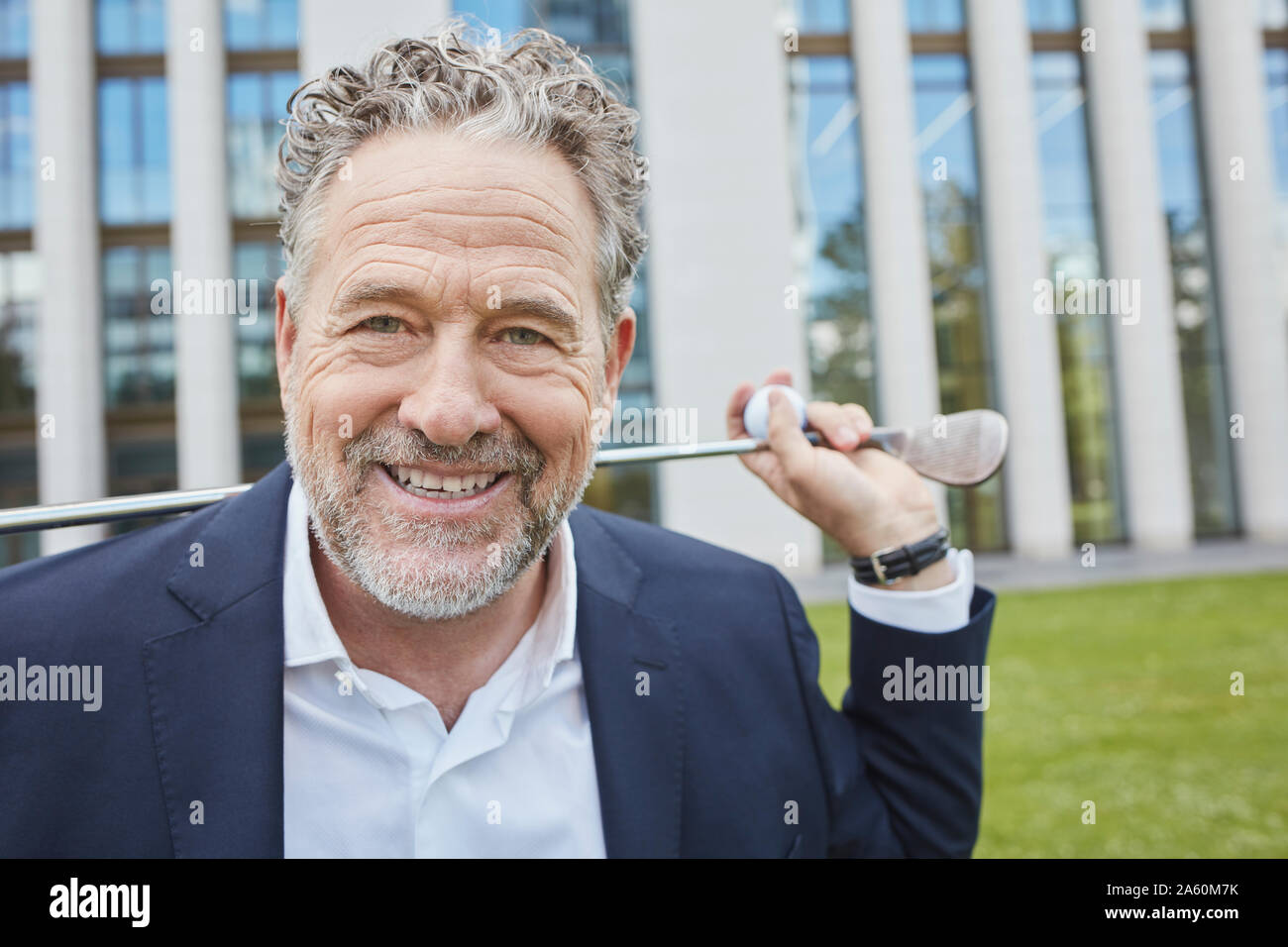 Portrait of happy mature businessman with golf club in the city Stock Photo
