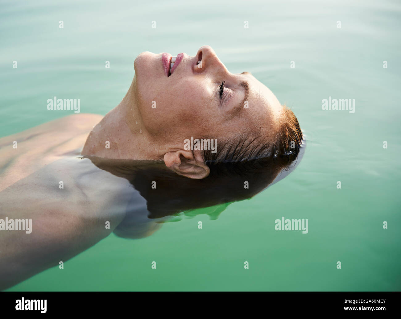 Mature woman floating in a lake with closed eyes Stock Photo