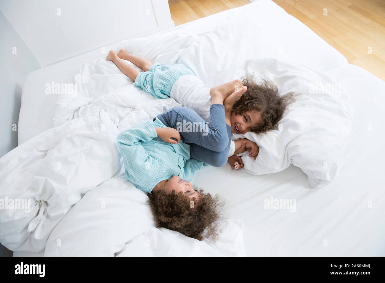 Two happy twin brothers romping around in bed Stock Photo