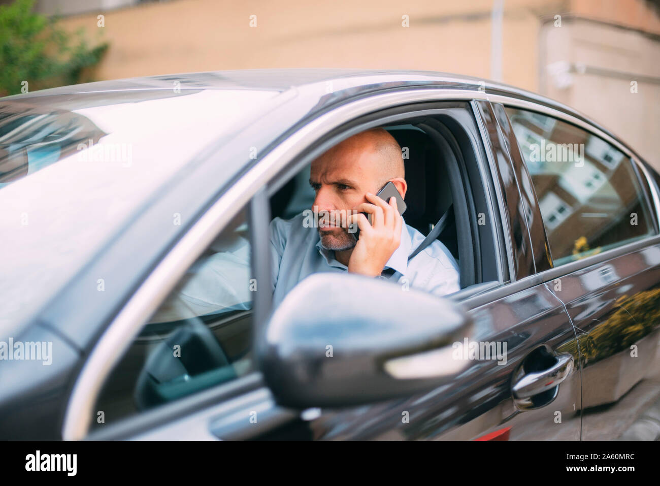 Businessman driving vehicle and using smartphone Stock Photo