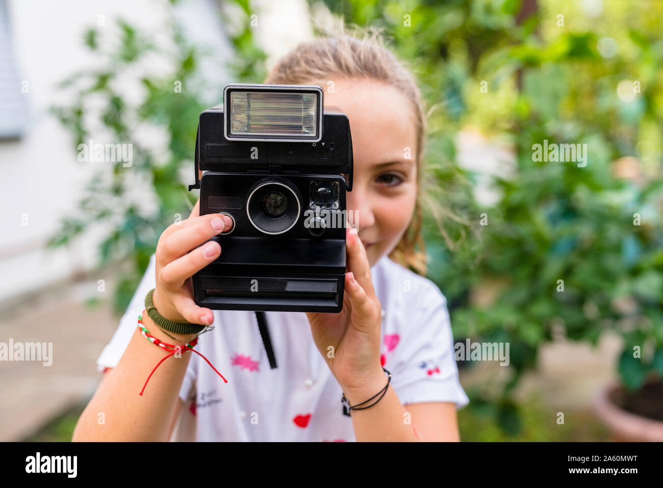 Girl taking a picture with an old-fashioned camera outdoors Stock Photo