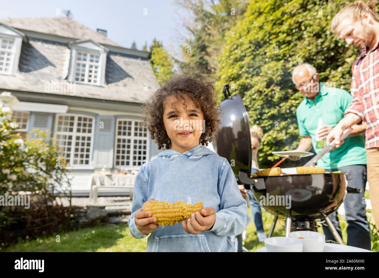 Portrait of boy with corn cob on a family barbecue in garden Stock Photo
