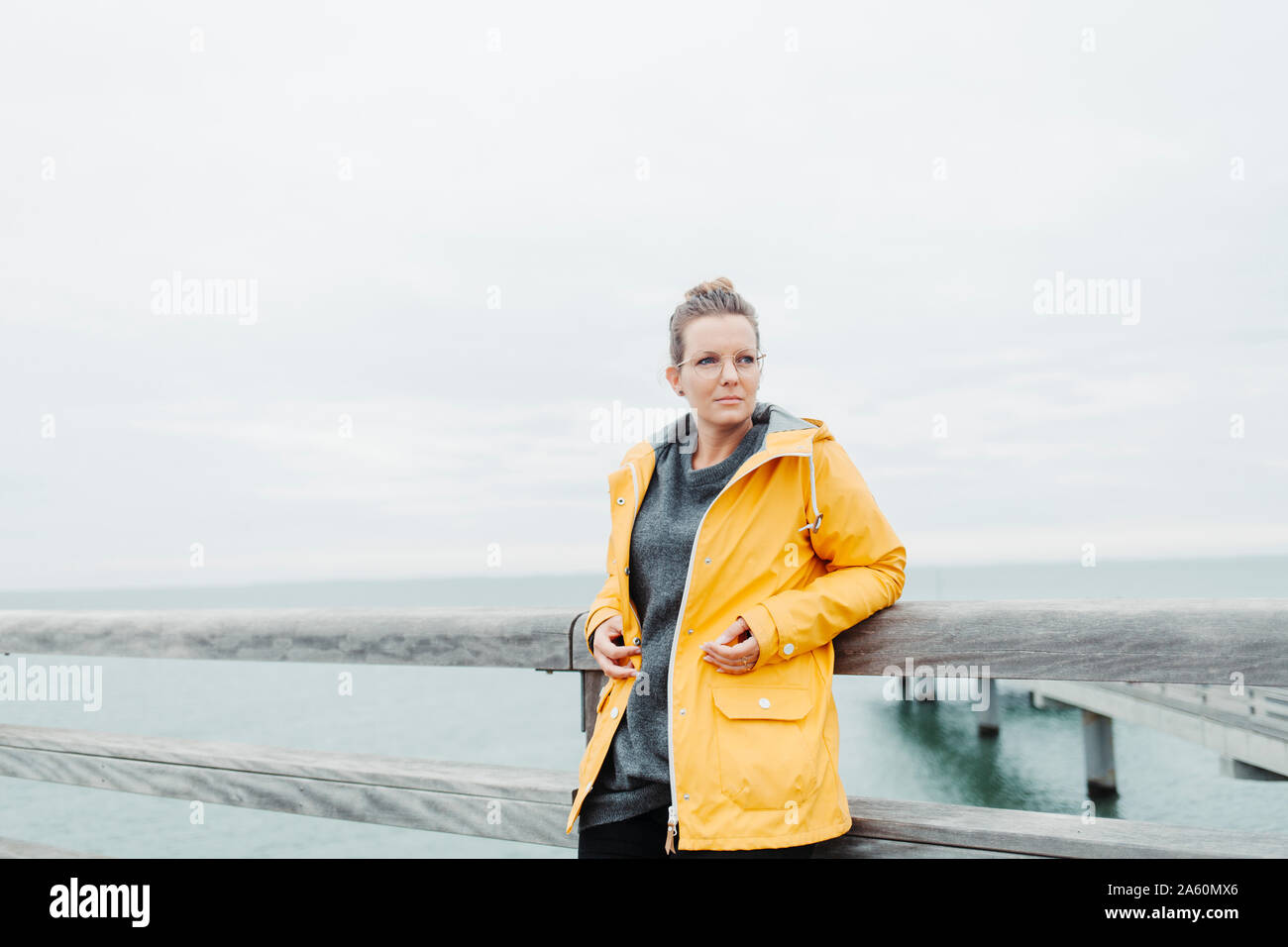 Young woman wearing yellow rain coat Stock Photo - Alamy