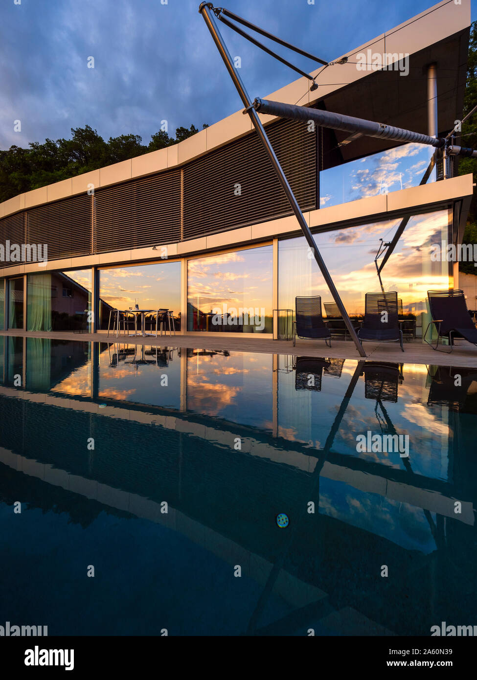 Switzerland, glass front of modern villa at dusk with terrace and pool in the foreground Stock Photo