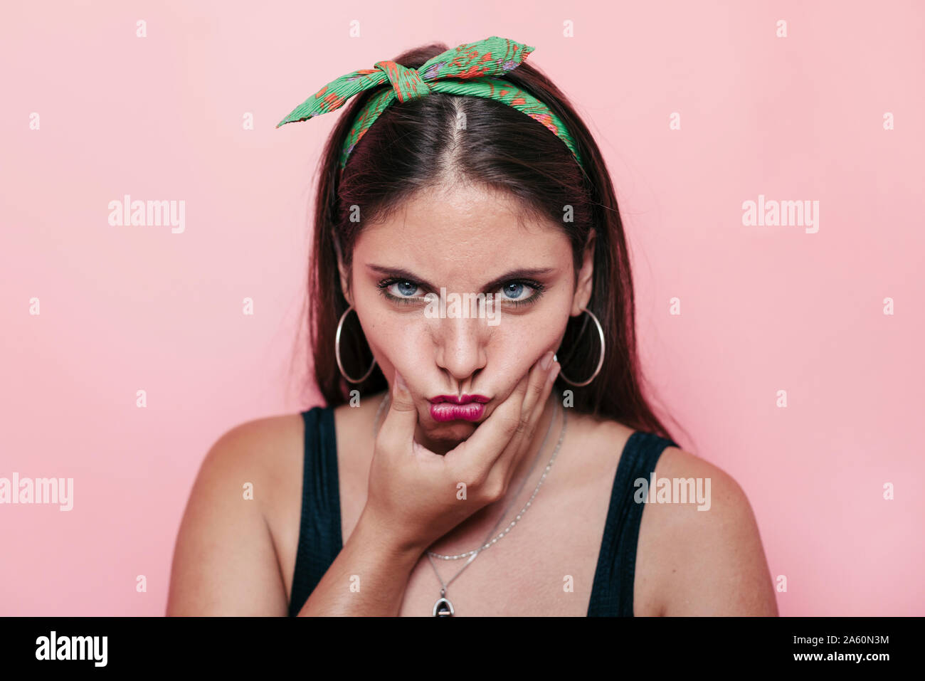 Young woman with blue eyes looking at the camera and making a silly angry face Stock Photo