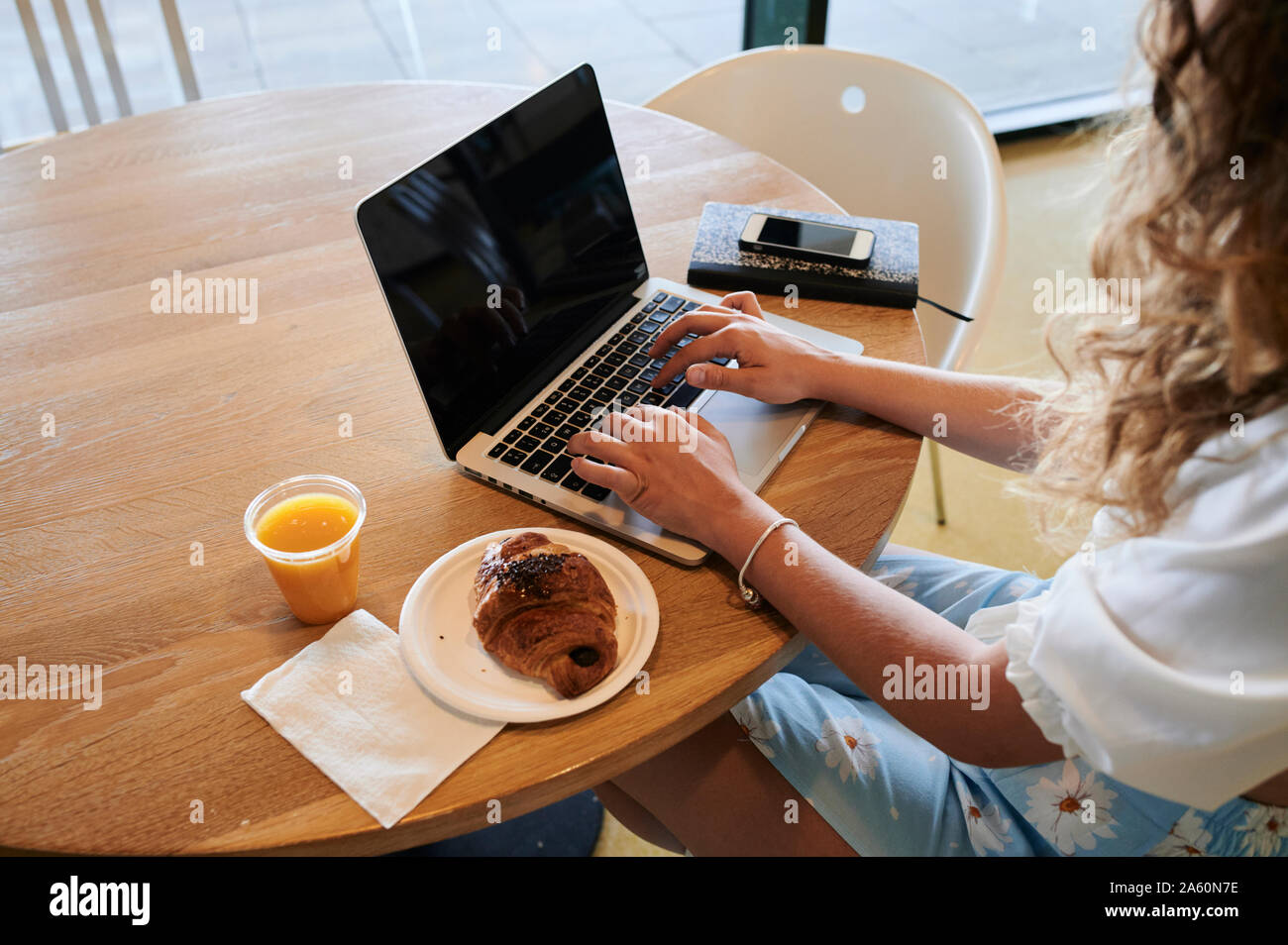Young woman in a cafe using laptop while having breakfast Stock Photo