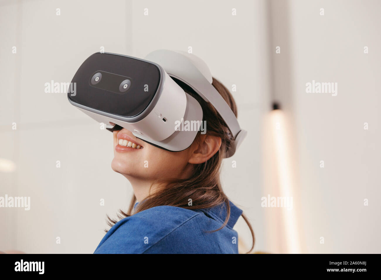 Young woman using VR glasses at home Stock Photo
